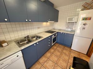 a kitchen with blue cabinets and a sink and a refrigerator at Les Dunes 5081 in Torroella de Montgrí