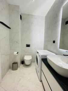 uma casa de banho branca com um lavatório e um WC em 19th floor Apartment em Cluj-Napoca