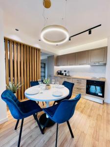 a dining room with a white table and blue chairs at 19th floor Apartment in Cluj-Napoca