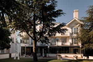 um edifício com uma árvore em frente em Hotel PAX Torrelodones em Torrelodones