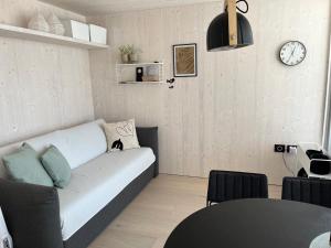a living room with a couch and a clock on the wall at BUQEZ ECO RESORT - Beach Villas 2 and 8 - Seaview, new wifi! in Drage