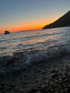 a beach at sunset with a boat in the water at BUQEZ ECO RESORT - Beach Villas 2 and 8 - Seaview, new wifi! in Drage