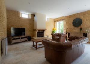 uma sala de estar com um sofá e uma televisão em Gîte du Manoir de Berville em Saint-Pierre-sur-Dives