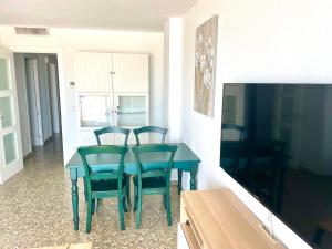 a dining room table with four chairs and a television at Apartamento TalaMar Gandia Playa in Playa de Gandia