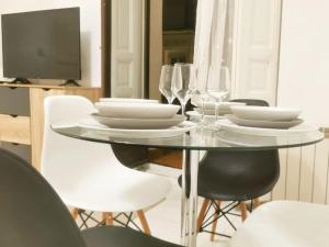 una mesa de comedor con platos blancos y copas de vino en Alojamiento en Centro de Madrid, en Madrid