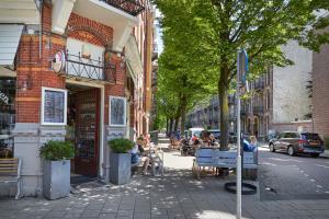 une rue avec des personnes assises sur des bancs devant un bâtiment dans l'établissement Nova Apartments Amsterdam, à Amsterdam