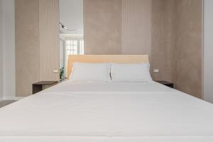 - une chambre avec un grand lit et des draps blancs dans l'établissement Marina Luxury Apartments Durrës, à Durrës
