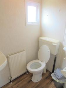 a bathroom with a white toilet and a window at Seaview: The Crown:- 6 Berth, Central heated, Enclosed Veranda in Ingoldmells