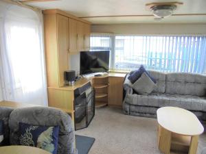 a living room with a couch and a tv at Seaview: The Crown:- 6 Berth, Central heated, Enclosed Veranda in Ingoldmells