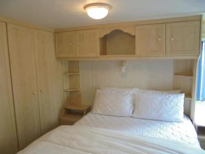 a bedroom with a white bed and wooden cabinets at Seaview: The Crown:- 6 Berth, Central heated, Enclosed Veranda in Ingoldmells