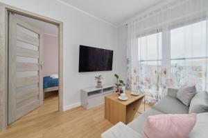 uma sala de estar com um sofá e uma televisão em Apartment Jesionowa with FREE GARAGE Wrocław by Renters em Breslávia