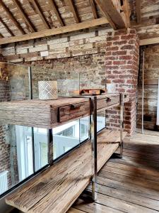 - une table en bois dans une chambre dotée d'un mur en briques dans l'établissement Luxury Spa Gîte - Loft Luxe, à Spa