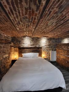 a bedroom with a large white bed in a brick wall at Luxury Spa Gîte - Loft Luxe in Spa