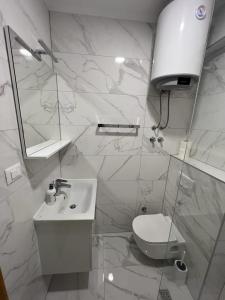 a white bathroom with a toilet and a sink at Apartments MAMPAS in Neum