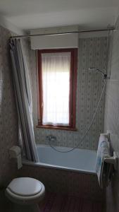 a bathroom with a tub and a toilet and a window at A due passi da Asiago... in Cesuna