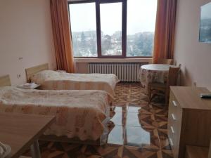 Habitación con 2 camas, mesa y ventana en Apart Hotel Central Razgrad, en Razgrad