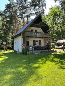 a small house with a porch on a lawn at Domek nad jeziorem - Białka in Białka