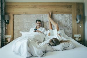 a man and a woman laying in bed with a book at hin&weg das Aparthotel in Ried im Zillertal