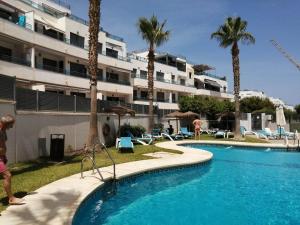 a swimming pool in front of a building with palm trees at Penthouse Spanje met Zeezicht Atico in Garrucha