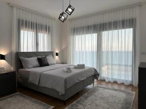 a bedroom with a large bed and large windows at Nejra Apartment in Ulcinj