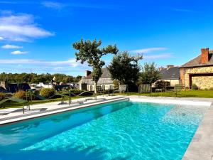 a swimming pool with blue water in front of a house at La Récréation - Chambres et Appartements in Châtelaudren