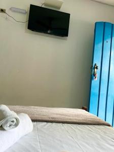 a bedroom with a bed with a flat screen tv on the wall at Pousada Marques in Paraty