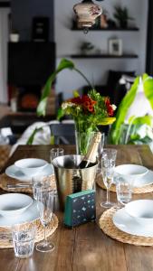 una mesa con platos y vasos y un jarrón de flores en Kamburinn Cottage en Hveragerði