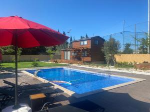 a swimming pool with a red umbrella and chairs at Cebel Tiny House&Bungalovs in Kemer