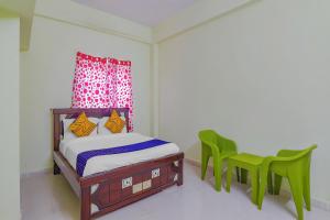 a bedroom with a bed and two green chairs at Flagship Sri Residency in Dhundgol