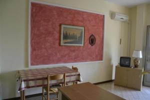 a living room with a table and a painting on the wall at Appartamento con piscina e tennis in Montespertoli