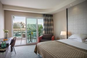 a hotel room with a bed and a balcony at Dan Panorama Eilat in Eilat