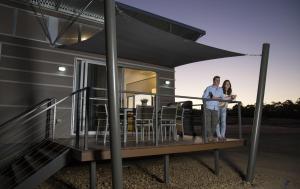 a man and woman standing on the deck of a house at Savannah Cabins, Taronga Western Plains Zoo in Dubbo