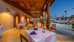 ein Restaurant mit Tischen und Stühlen und einem Pool in der Unterkunft Ghazala Gardens in Sharm El Sheikh