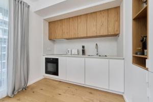 een keuken met witte kasten en een wastafel bij Walońska 16 Sauna & Fitness Family Apartments by Renters Prestige in Wrocław