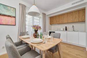 een keuken en eetkamer met een houten tafel en stoelen bij Walońska 16 Sauna & Fitness Family Apartments by Renters Prestige in Wrocław
