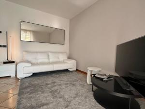 Il comprend un salon doté d'un canapé blanc et d'une télévision à écran plat. dans l'établissement Gioia Home, à Bardolino