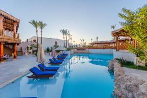 einen Pool in einem Resort mit blauem Wasser und Liegestühlen in der Unterkunft Ghazala Gardens in Sharm El Sheikh