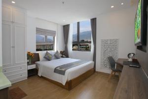 a bedroom with a bed and a desk and a window at Skylight Hotel Nha Trang in Nha Trang
