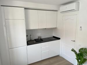 a white kitchen with white cabinets and a sink at Estudio al lado de la playa in Calafell