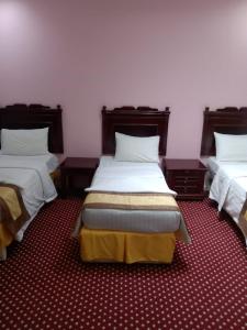 فندق روابي العزيزية-Rawaby Hotels في مكة المكرمة: غرفة نوم بسريرين مع شراشف بيضاء وسجادة حمراء