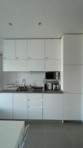 una cucina bianca con lavandino e forno a microonde di Seafront rooftop flat w/ terrace a Portovenere