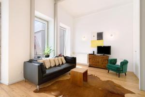 a living room with a black leather couch and a green chair at Casa Rosa in São Brás de Alportel