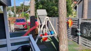 a playground with a slide and a tree at Domki Polarne in Dziwnówek +15 photos