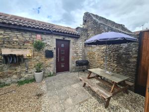 a picnic table with an umbrella in front of a building at Luxury Bumblebee Cottage Frome Longleat Aqua Sana Bath DOG FREEndly in Frome