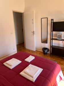 a bedroom with a red bed with two towels on it at Alvalade II Airport Guest House in Lisbon
