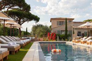 einen Pool mit Liegestühlen und ein Haus in der Unterkunft Hôtel L'Escalet in Ramatuelle