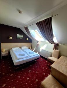 a hotel room with a large bed and a chair at Hotel Pajurio vieskelis in Klaipėda