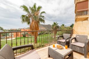 a balcony with chairs and a table and a palm tree at Trendy Homes Envia Golf I in La Envia