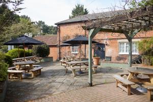 a group of picnic tables and umbrellas in front of a building at Kings Arms Hotel by Greene King Inns in Westerham