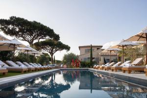 a swimming pool with lounge chairs and umbrellas at Hôtel L'Escalet in Ramatuelle